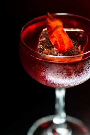 A beautiful closeup shot of a glass with a red cocktail on  a dark background
