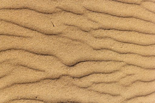 A high angle shot of a rough golden beach sand texture