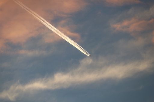 A long jet stream against pinkish clouds in the sky