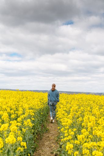 A vertical shot of a female walking in the field with a dog
