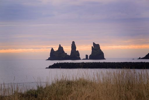 A golden sunset over the rocky cliff in the ocean in Iceland