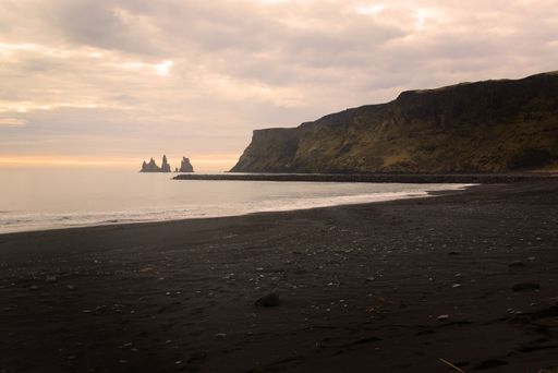 A golden sunset over the rocky cliff in the ocean in Iceland
