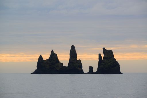 A golden sunset over the rocky cliff in the ocean in Iceland