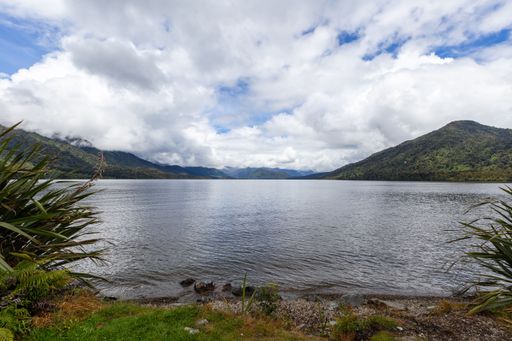 A beautiful shot of a lake with nearby green mountains under a cloudy sky