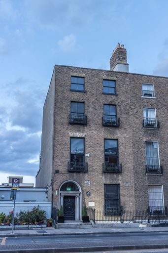 A vertical shot of an old brick building against a gray cloudy sky in Dublin