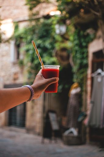 A vertical shot of a hand holding a cup with fresh cold refreshing juice