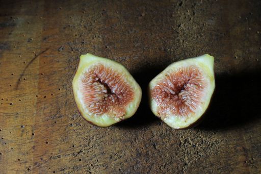 A closeup shot of a black fig cut in half on a dark wooden board
