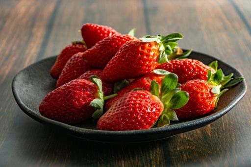 A closeup shot of fresh and delicious strawberries on a dark plate