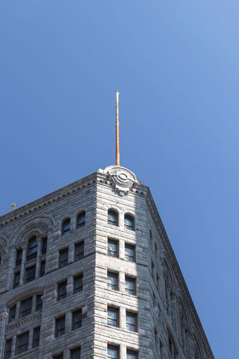 A vertical shot of an old classic building with an empty flag pole on the top