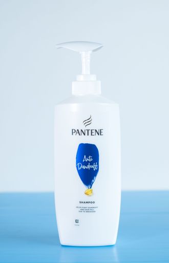 A Pantene shampoo bottle on a blue background
