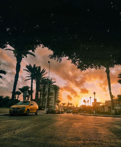 A vertical low angle shot from the street of cloudy orange sunset sky