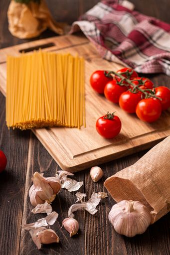 A vertical shot of all the ingredients laid out needed for making pasta with tomato sauce