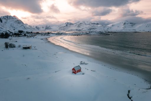 Aerial Drone shot of the Red Shed at Ramberstranda in the Lofoten Islands during winter at sunset on an overcast day.