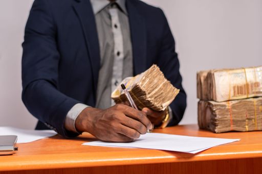 A rich African businessman filling in a paycheck at his desk at work