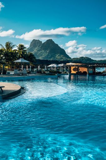 A vertical shot of a resort with a pool in Bora Bora with Mount Otemanu in the background