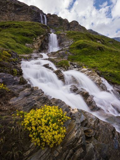 A vertical shot of a waterfall in Grossglockner mountain range with rocks