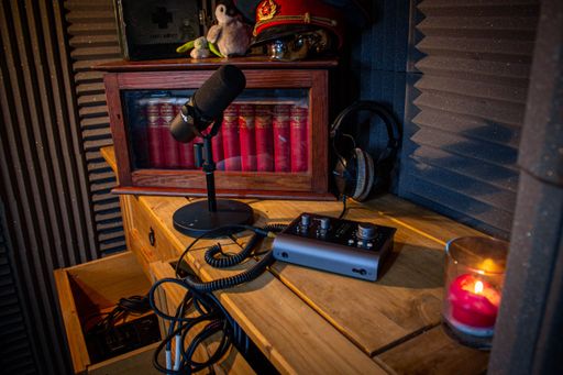 A Shure microphone, cable, Audient Interface, and a pair of Beyerdynamic headphones in the studio