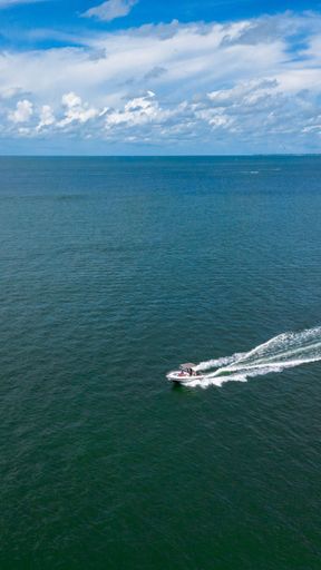 A vertical shot of a yacht sailing in the ocean
