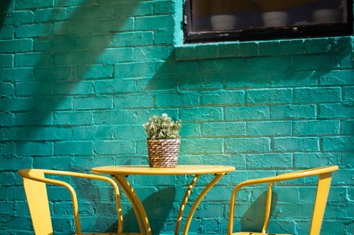 A yellow table with chairs against a turquoise brick wall