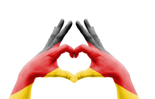 The two hands of a person painted with the flag of Germany forming a heart isolated on a white background