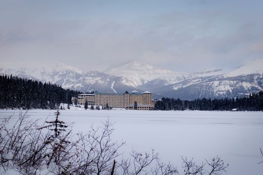 A beautiful shot of the Fairmont Chateau Lake Louise in winter with mountains in the background