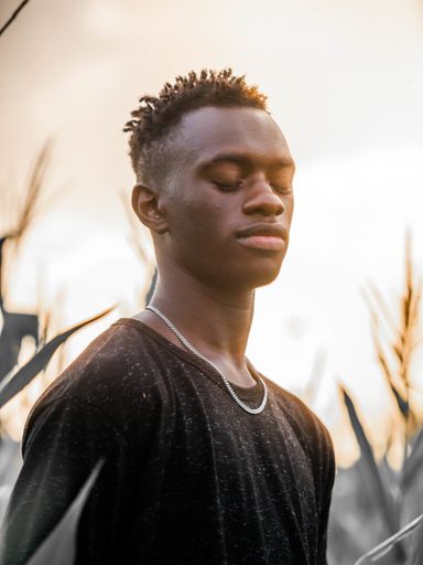 A shallow focus shot of a young black male on a beautiful sunset background