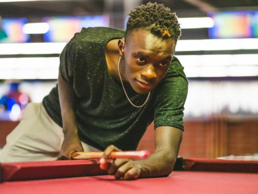 A shallow focus shot of a young black male in a billiards playroom