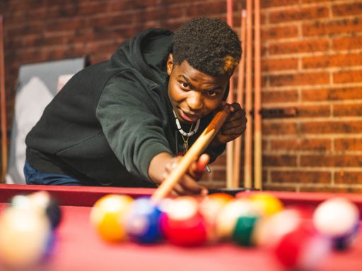 A shallow focus shot of a young black male in a billiards playroom