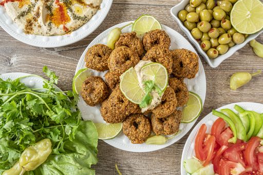 A top view of falafel fries, olives, vegetables and herbs on wooden table