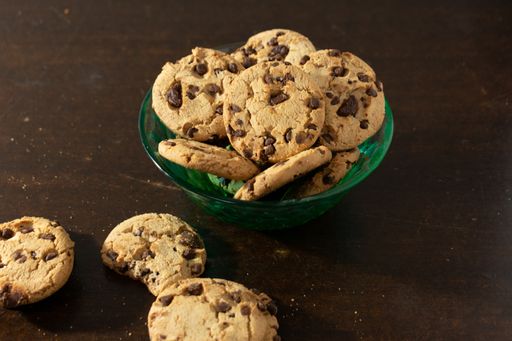 A closeup of chocolate chip cookies in a bowl on a wooden table