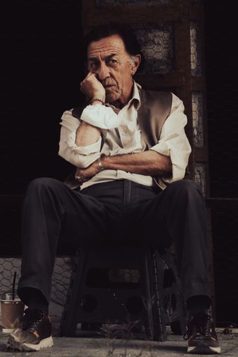 The vertical shot of a mature man sitting thoughtfully before the darkness