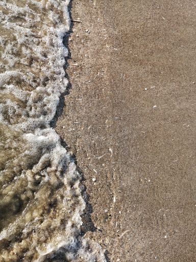 A high angle shot of the foamy water of the sea on the wet sand