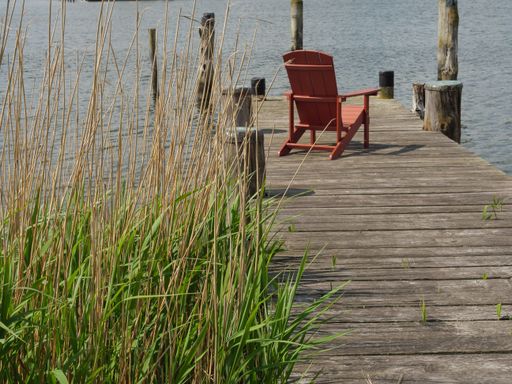A wooden dock with a red folding chair alongside the river in Schleswig-Holstein, Germany