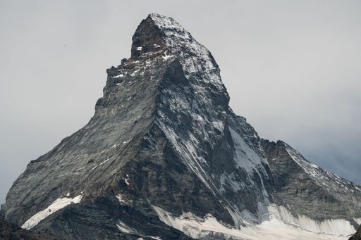 A scenic view of the snow-capped peak of the Matterhorn mountain against cloudy sky in Zermatt Village, Switzerland