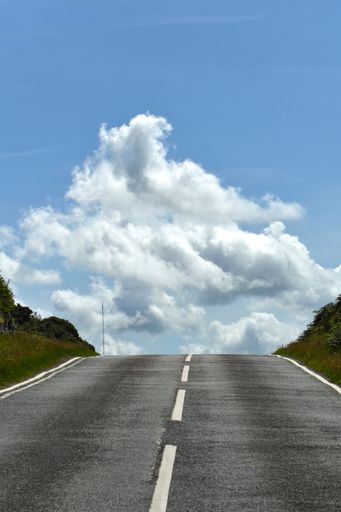 A vertical shot of a road leading to the crest of a hill under the dramatic skyline in North Wales