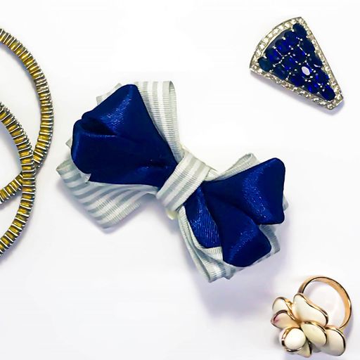 An isolated closeup shot of a blue and white bow tie next to other accessories on a white background