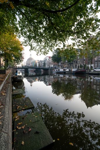 A vertical shot of a canal in the city of Amsterdam, the Netherlands