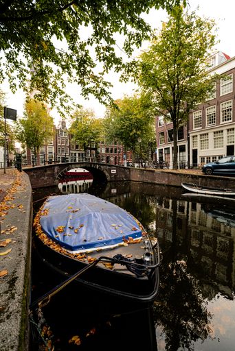 A vertical shot of a boat in the canal in the city of Amsterdam, the Netherlands