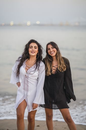 A portrait of two sexy females wearing black and white dresses while enjoying the beach