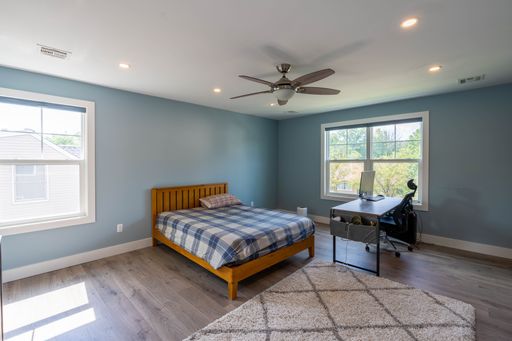 An interior of a modern renovated and furnished bedroom with two big windows