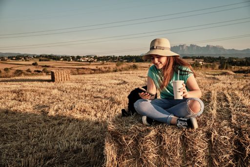 A selective focus shot of a young girl with round hat sitting and looking at the phone