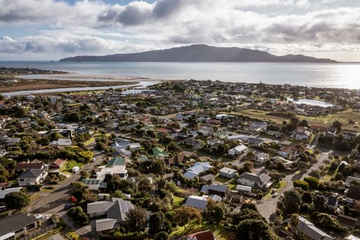 Waikanae beach and Kapiti Island from the river estuary to the housing of the Old Beach. Cloudy afternoon with late sun causing lens flare