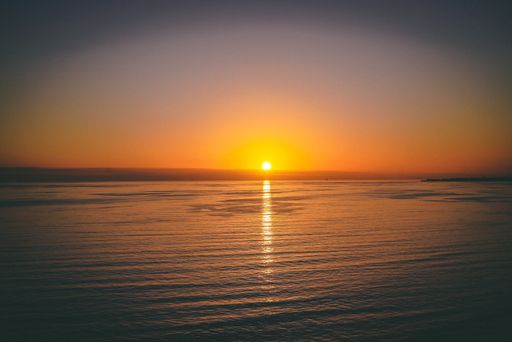 A beautiful shot of the calm sea with the bright sun setting in the background
