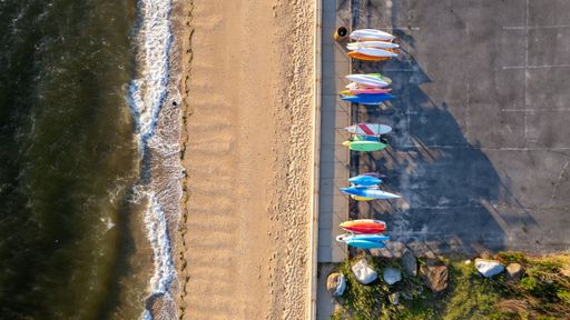 An aerial view of sunrise on gold coast of Long Island, New York, over empty beach with colorful kayaks
