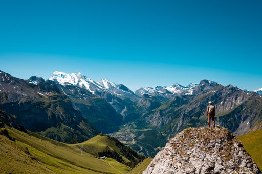 A hiker standing on the Bernese Oberland hiking ridge with mountain landscape in Switzerland