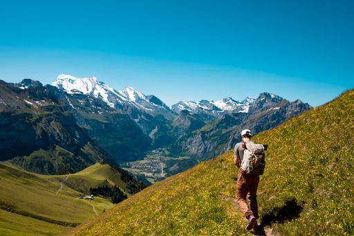 A hiker standing on the Bernese Oberland hiking ridge with mountain landscape in Switzerland