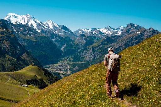 A hiker standing on the Bernese Oberland hiking ridge with mountain landscape in Switzerland