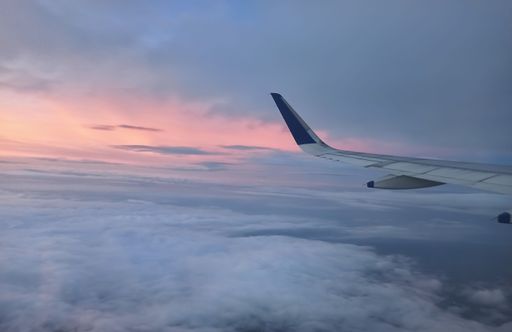 A Scenic View of the Wings of a aero plane flying above the clouds. Travelling by aero plane during sunset.