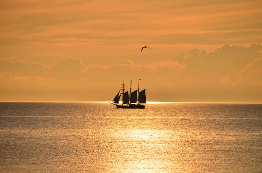 A silhouette of floating boat in sea during sunset