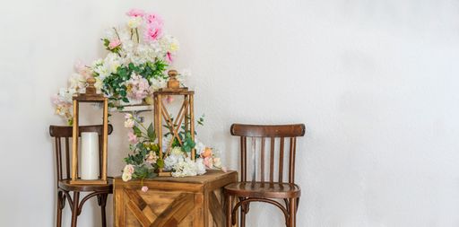 Designer corner in an apartment in wedding style. Wooden chairs, bouquets of flowers, decorative street lamps with paraffin candles.